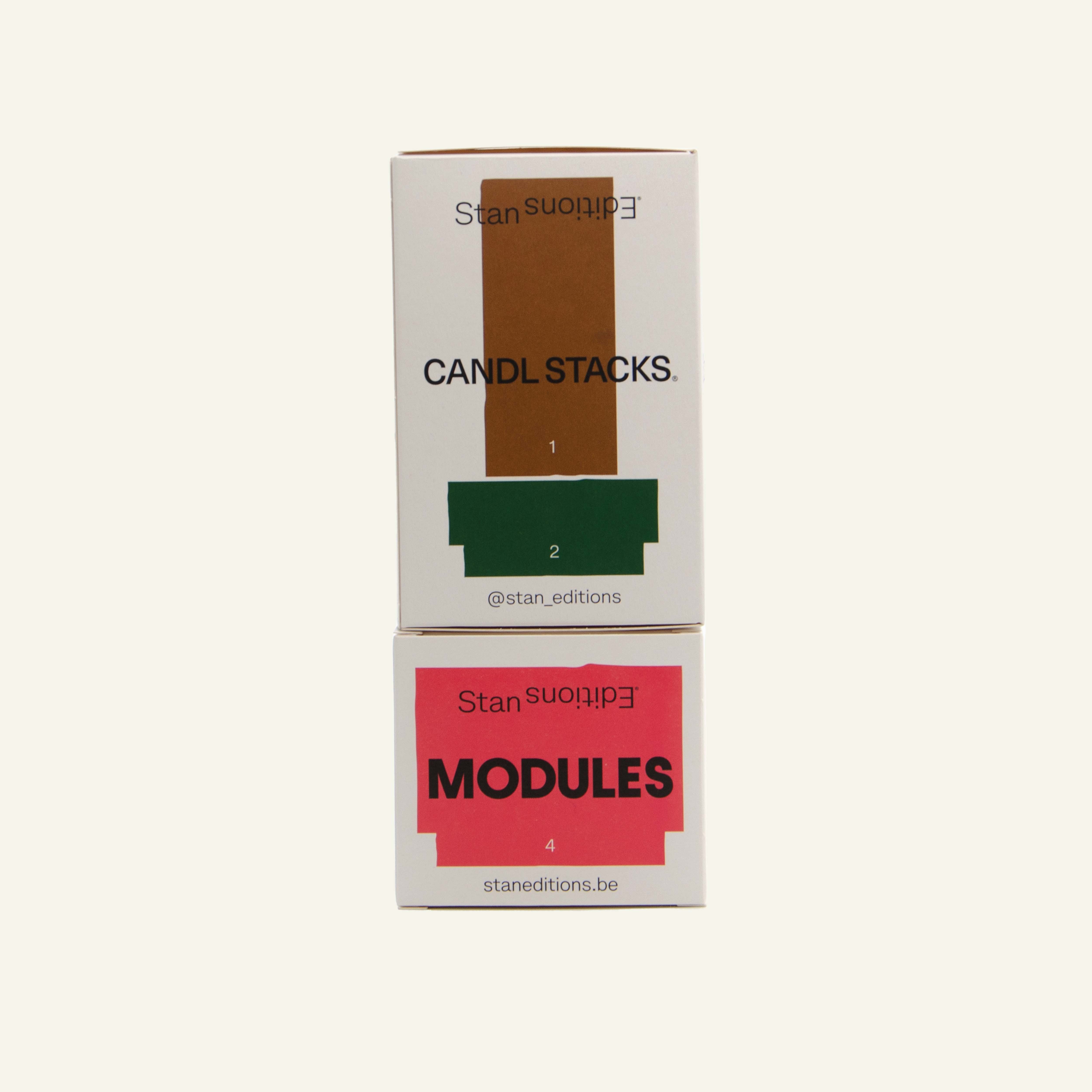 Verpakkingen van een bruin/groene en een rode Stan Edition kaars op elkaar gestapeld.